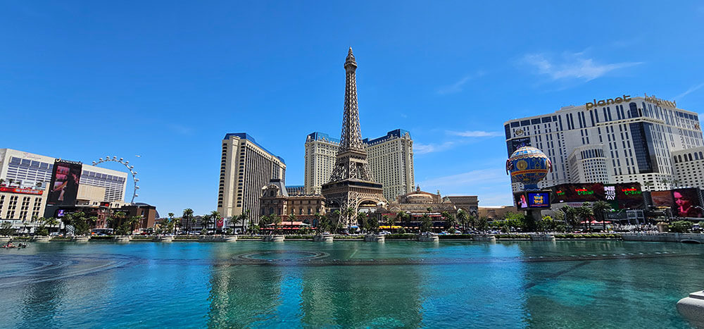 Las Vegas buildings, including an Eiffel Tower replica. Blue skies with puffy white clouds.