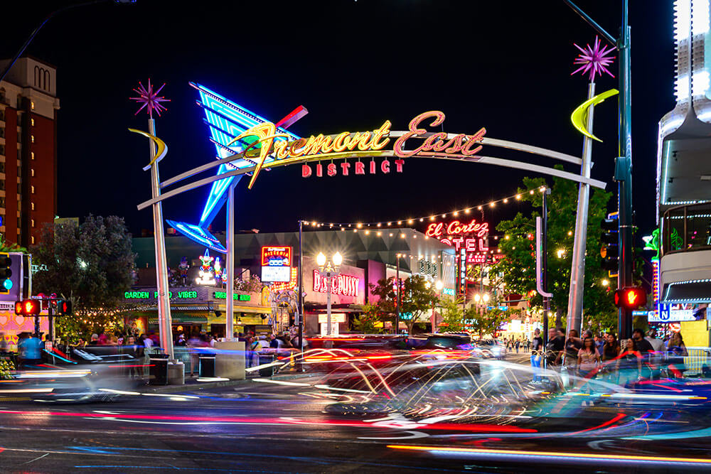 Long exposure shot of a Las Vegas street at night. Neon lights, traffic, and people.