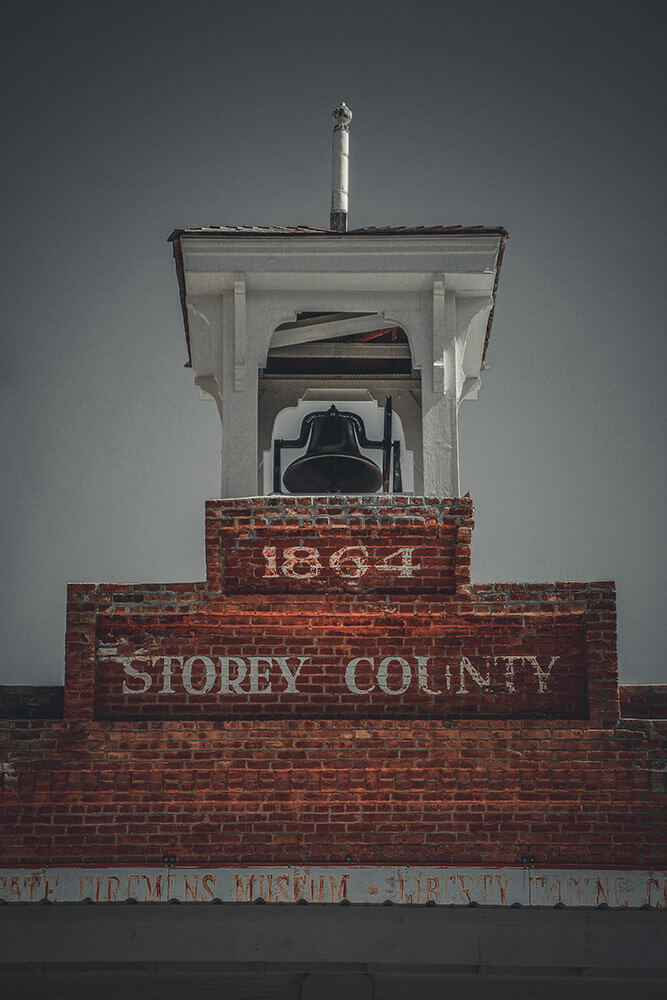 A brick building with a bell tower. On the bricks is painted "1864 STOREY COUNTY"