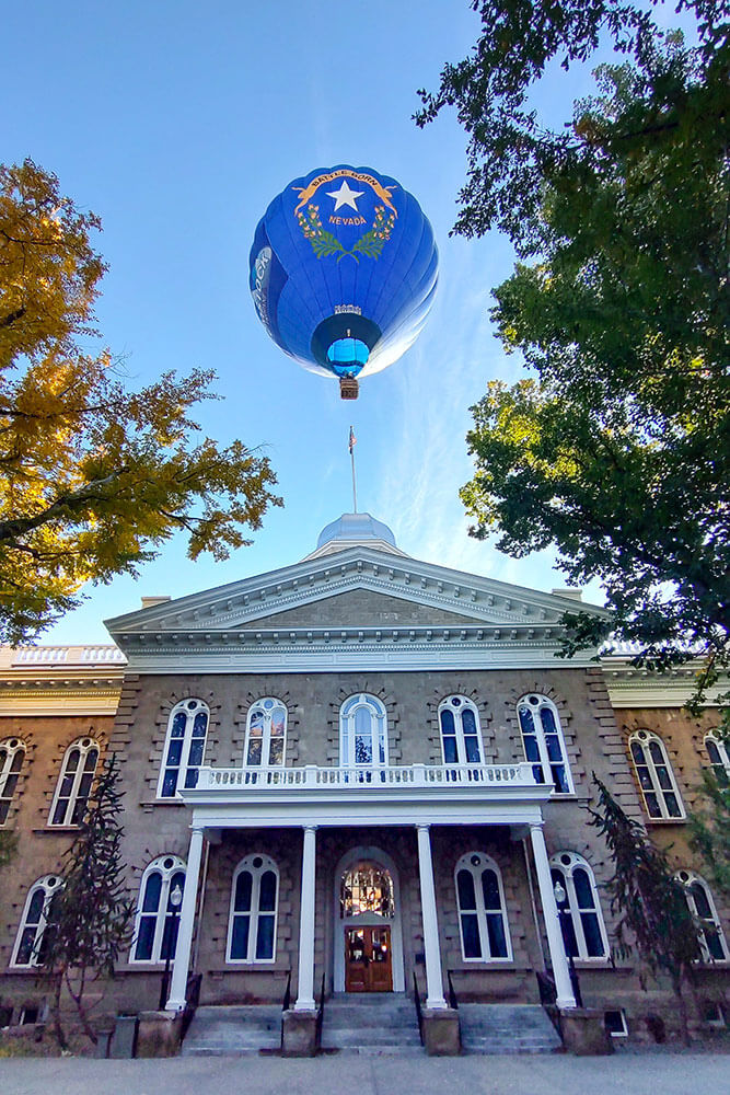A hot air balloon with a Battleborn Nevada design rises above the state Capitol building.