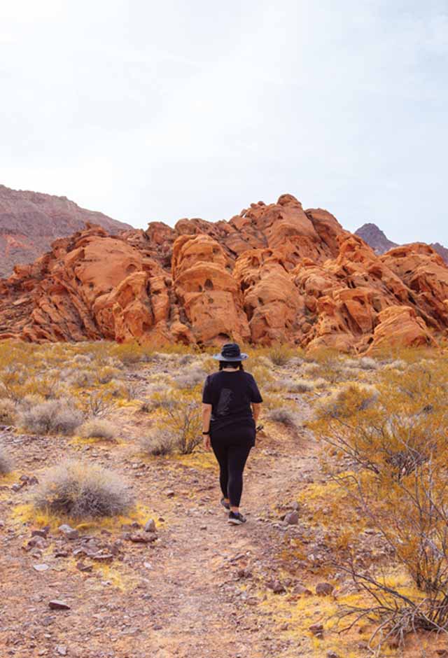Woman walking towards red rocks along the Redstone Discovery Trail at Lake Mead National Recreation Area.
