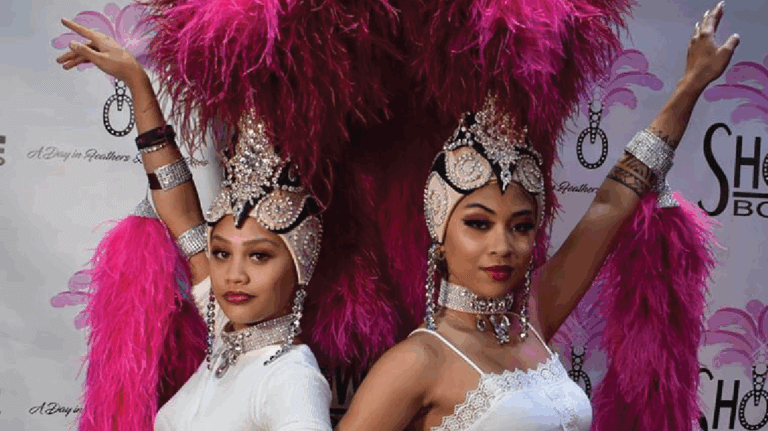 Two women pose for a photo dressed as showgirls