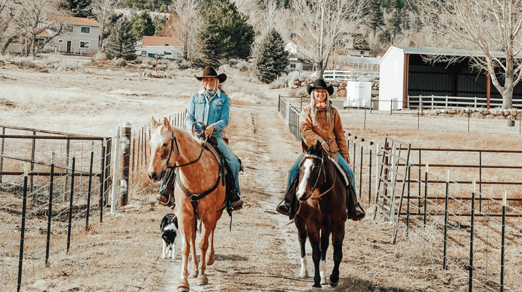 Two women are seen riding horses.