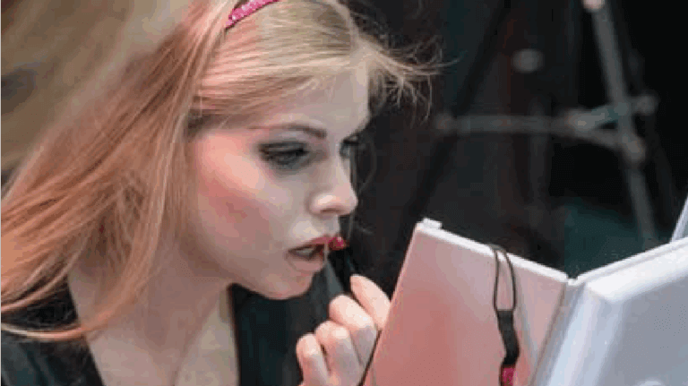 A women looks at the mirror as she applies her makeup