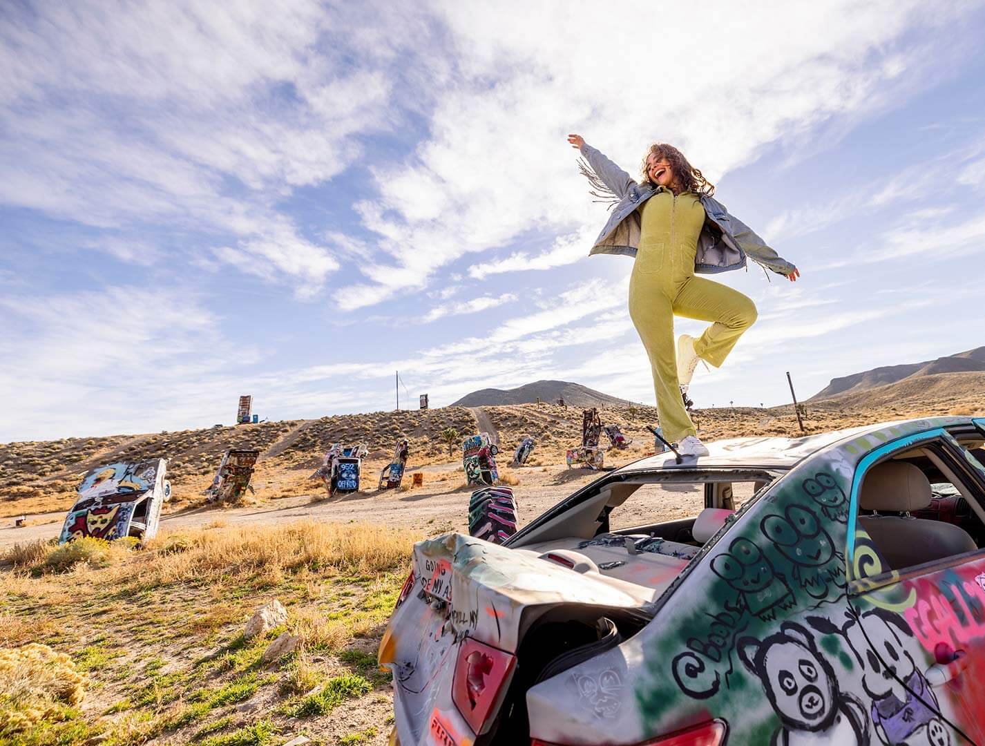 woman dancing on a car at the international car forest of the last church in goldfield nevada