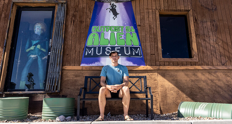 alex honnold sitting outside of the alien museum in southern nevada