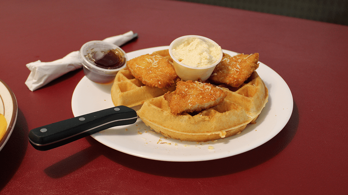 A plate from Strawberry Hill Diner shows chicken and waffles plate, complete with butter and syrup on the side.