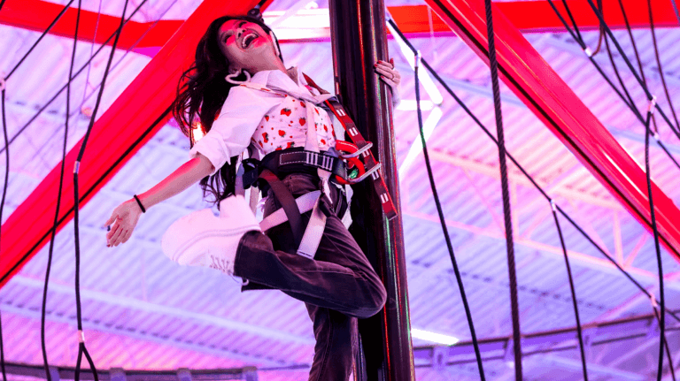 A woman climbs one of the features in Spy Ninja HQ, smiling.