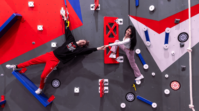 A man and woman touch hands while climbing one of the rock/climbing walls.