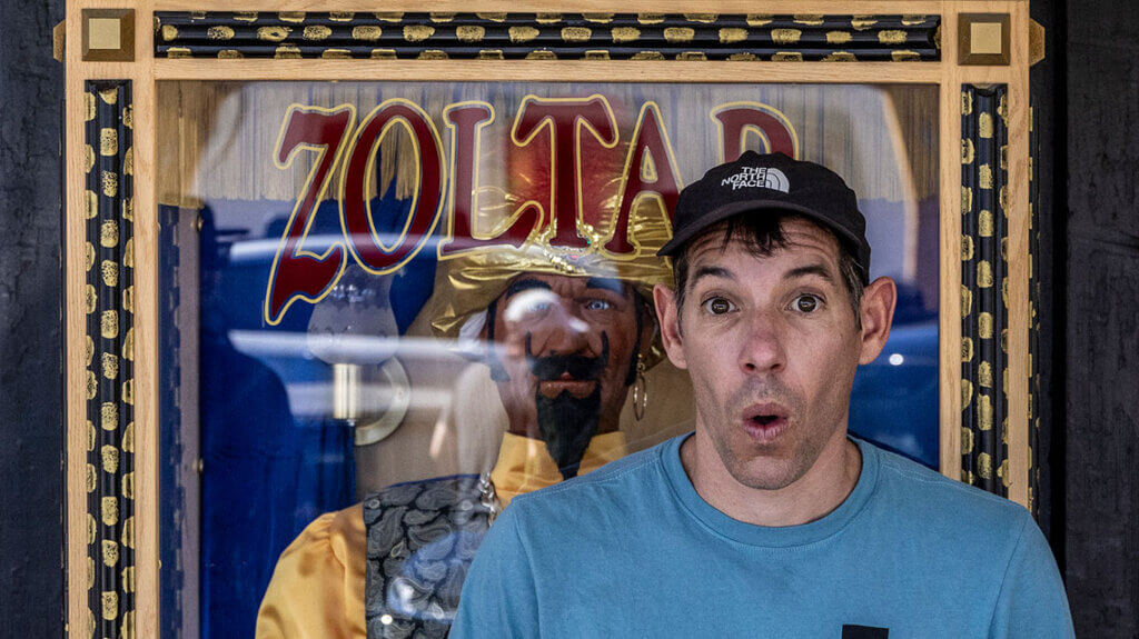 alex honnold posing with a zoltar machine in boulder city nevada as part of the outside series get a little out there with alex honnold