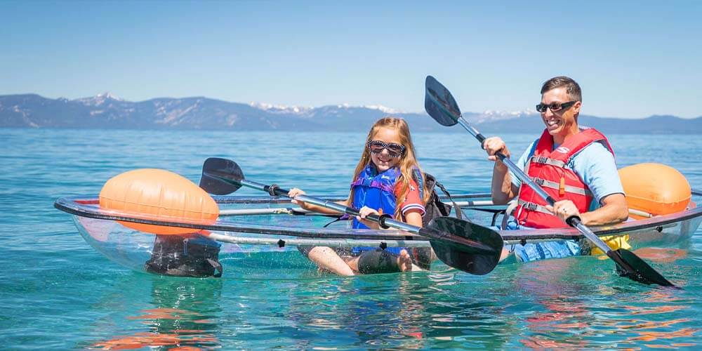 family in clear kayaks at lake tahoe