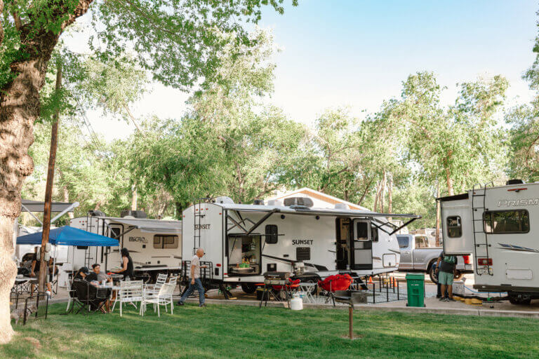People eating at a table on a lawn outside of their RVs at River West Resort.