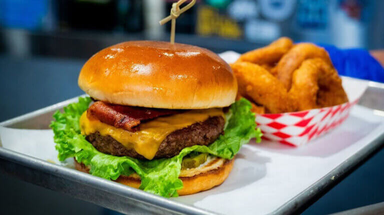 A hamburger with onion rings on the side.