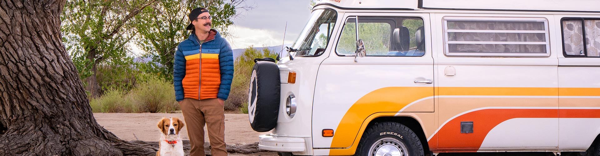man, campervan, and dog under a tree on the loneliest road in america in nevada