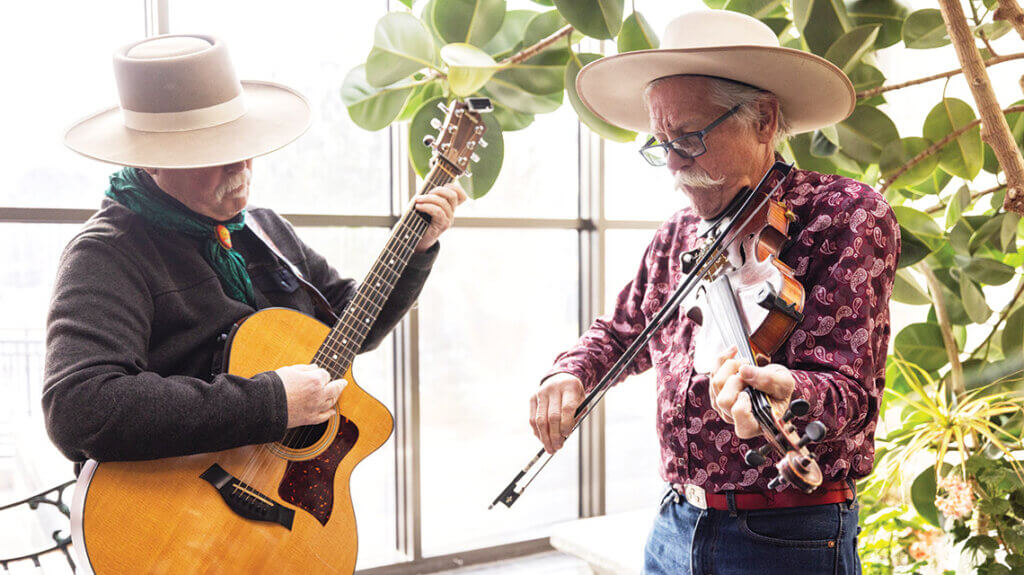 a guitarist and a fiddler jam in the lobby of the Elko Convention Center at Cowboy POetry.
