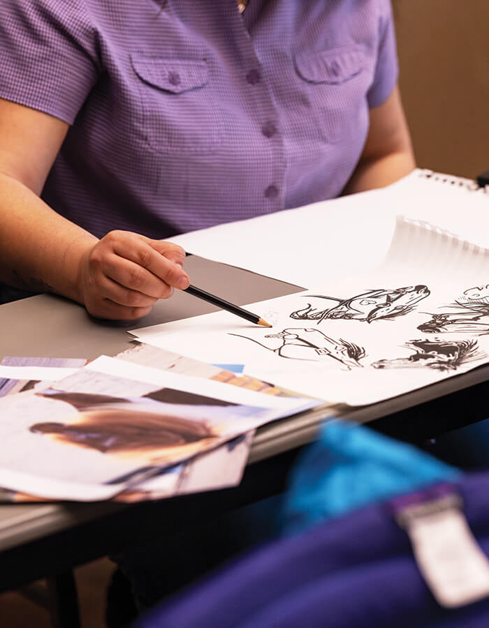 Hands working on a drawing at Cowboy Poetry in Elko