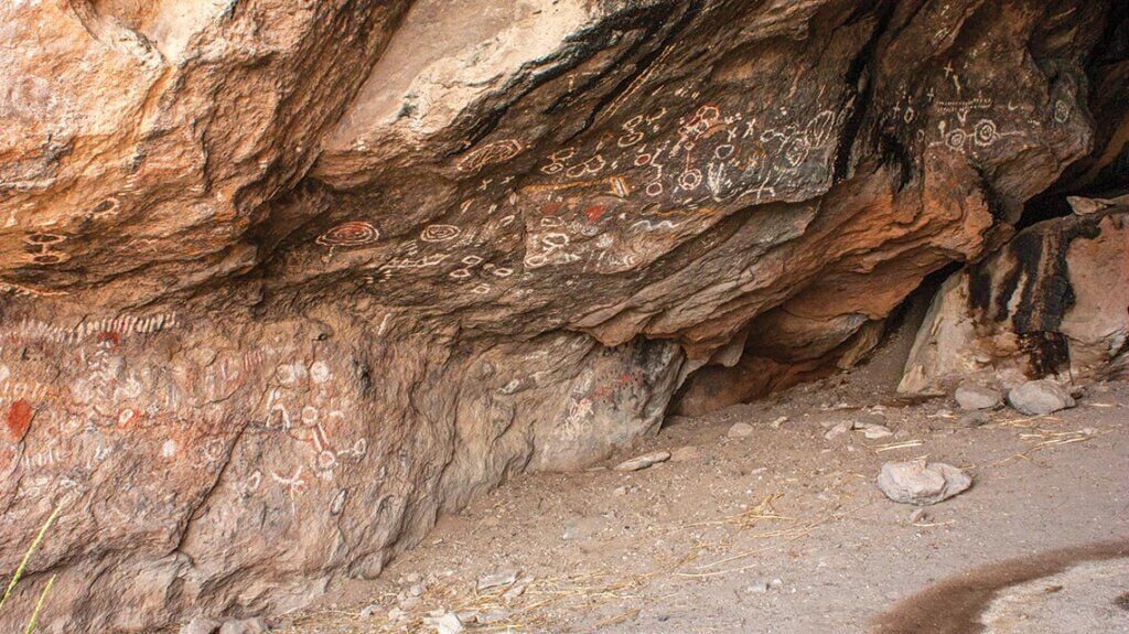 The interior of Toquima Cave in Nevada with pictographs of red, white, and yellow on the walls. 