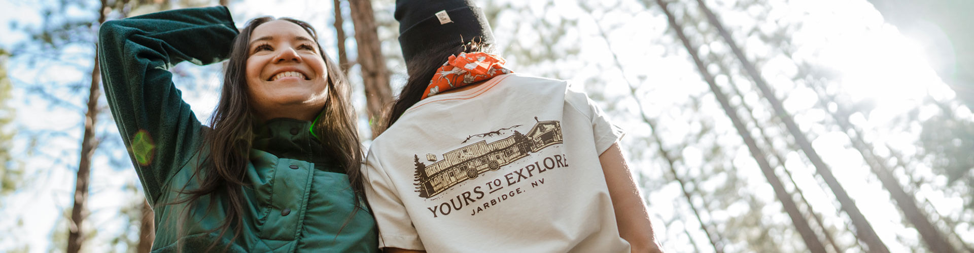 two women in a forest wearing deso supply co x travel nevada merch